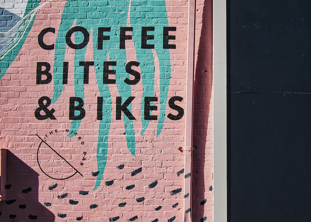 a pink brick wall with a sign that says coffee bites and bikes