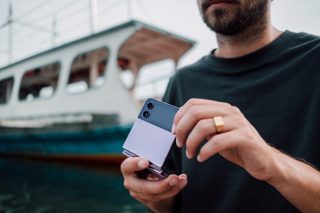 a man holding a cell phone in front of a boat