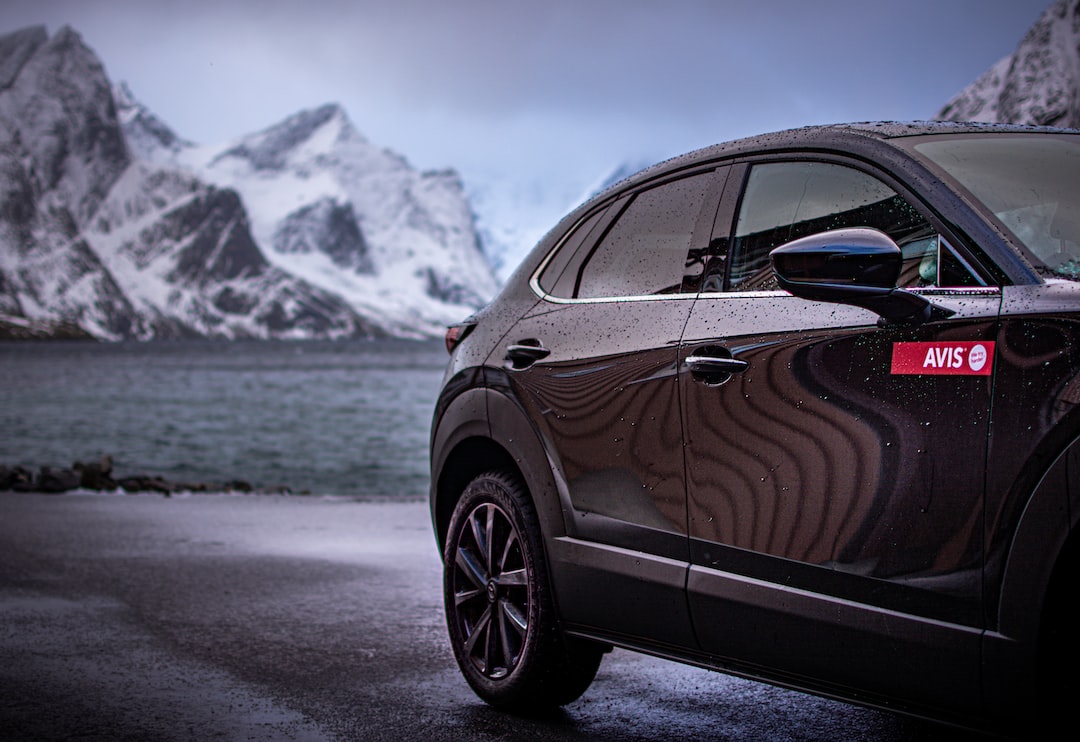 a car parked on a road by water and mountains