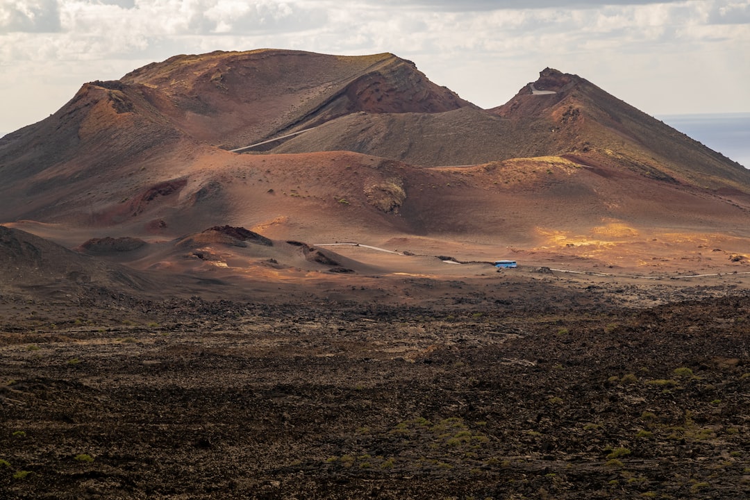 a group of mountains in the desert under a cloudy sky