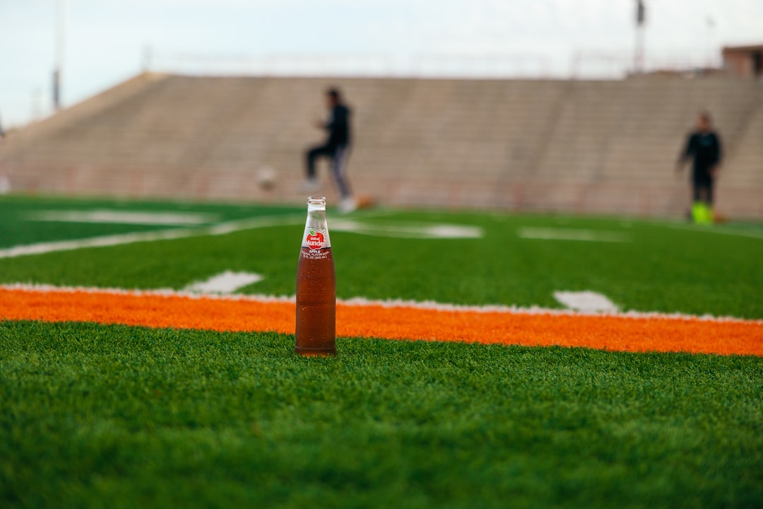 a bottle of soda sitting on top of a green field