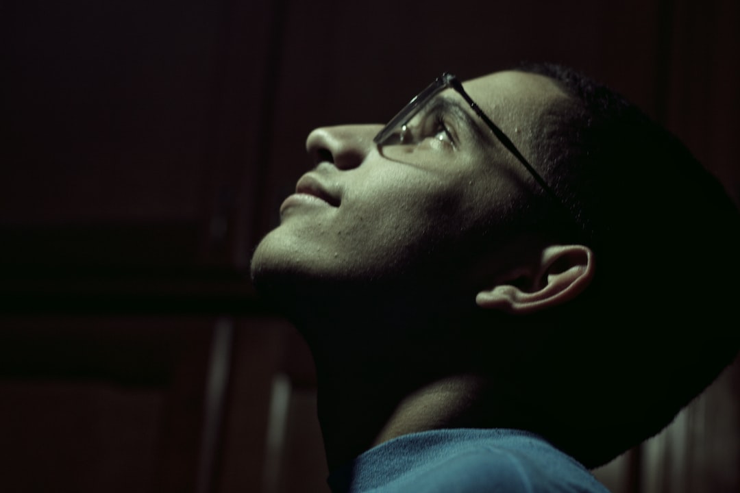 a man with glasses looking up into the sky