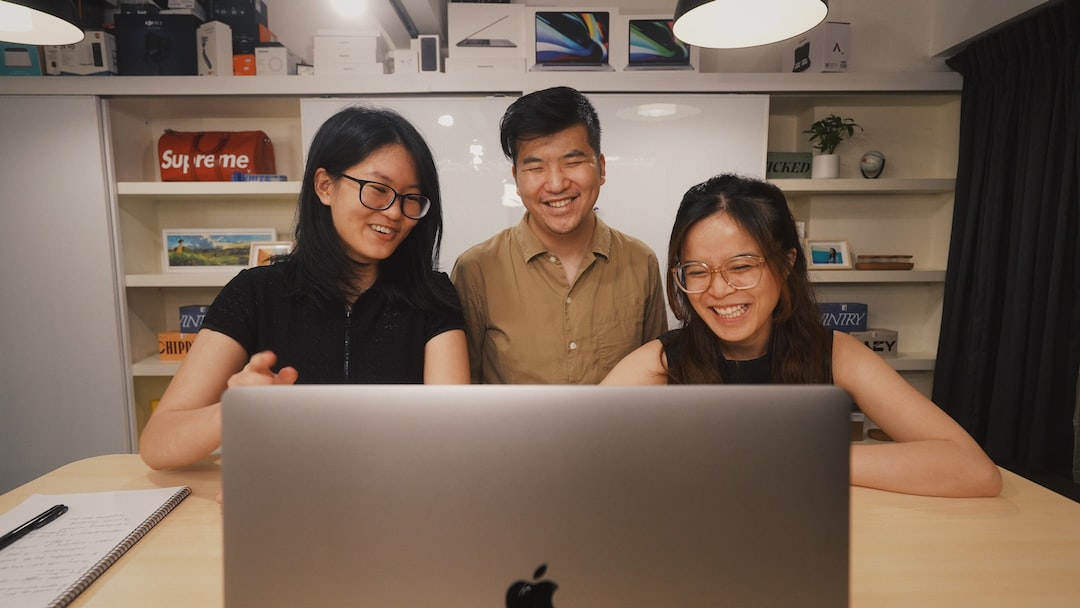 a group of three people standing in front of a laptop computer