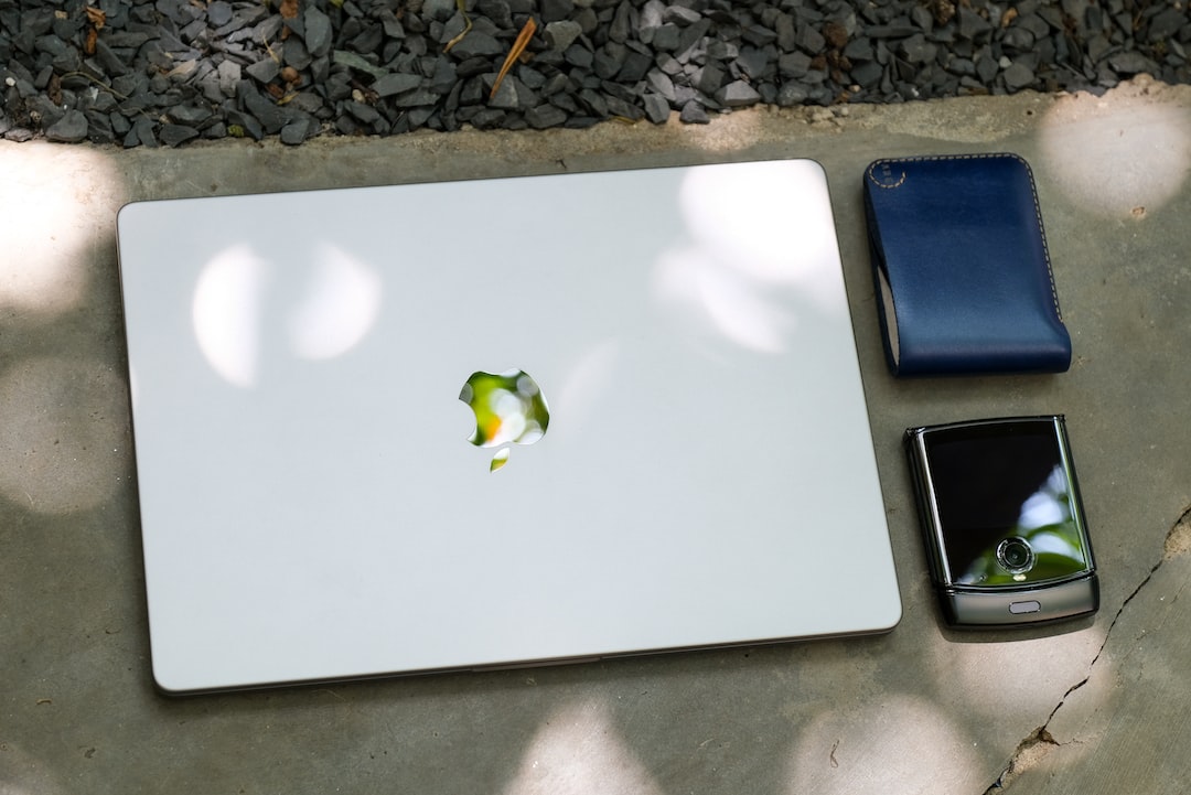 a white laptop computer sitting on top of a table next to a cell phone