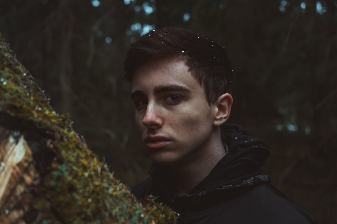 man in black hoodie standing near green plant