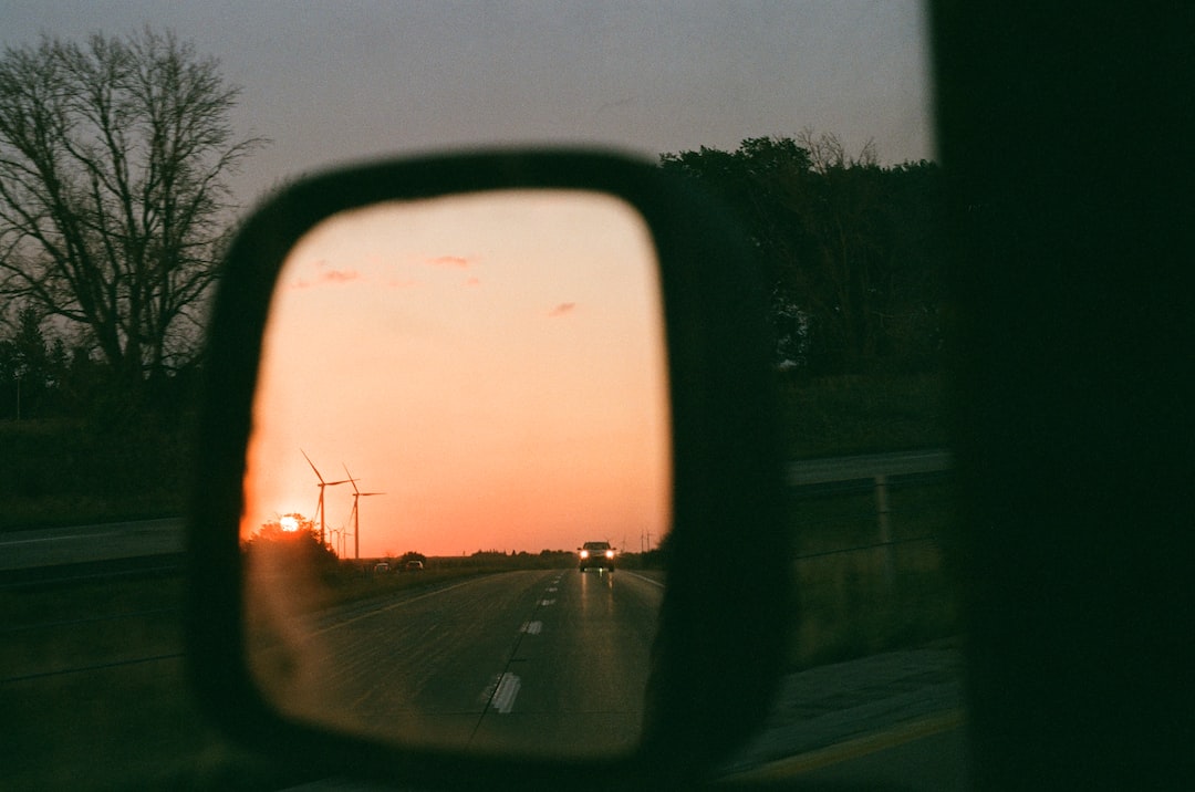 a car's side view mirror reflecting a sunset