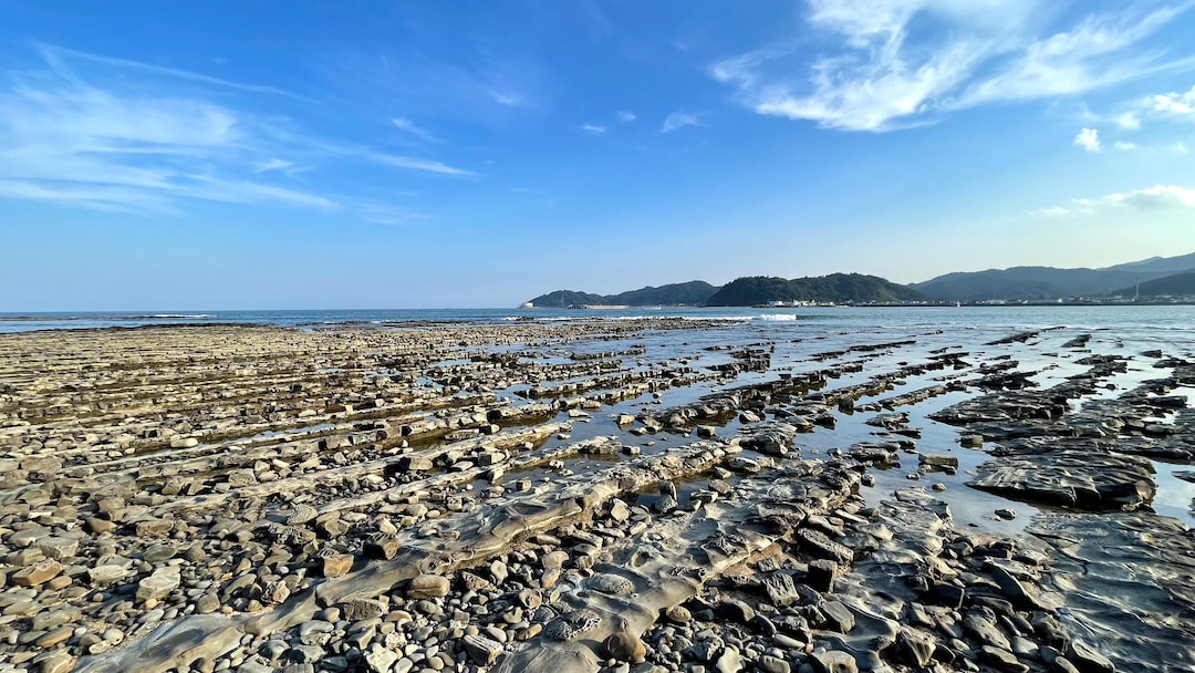 a beach with rocks and water under a blue sky