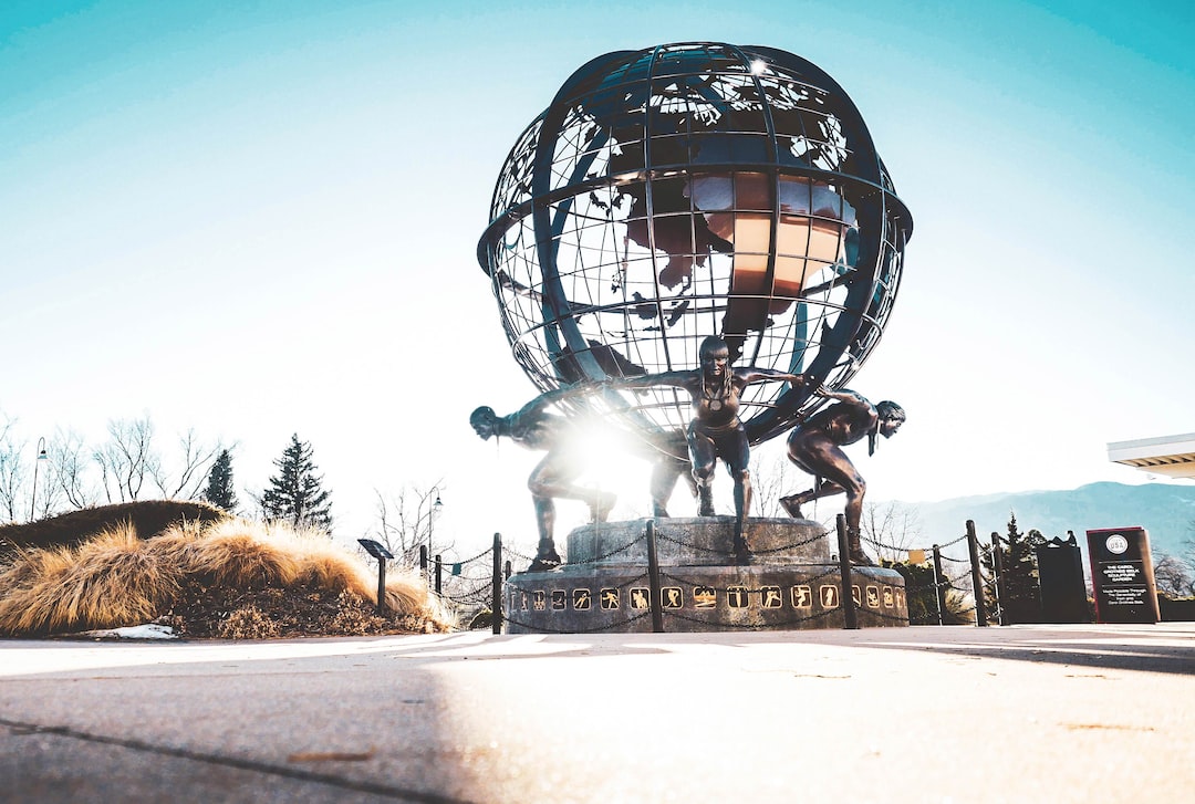 men carrying globe statue during daytime