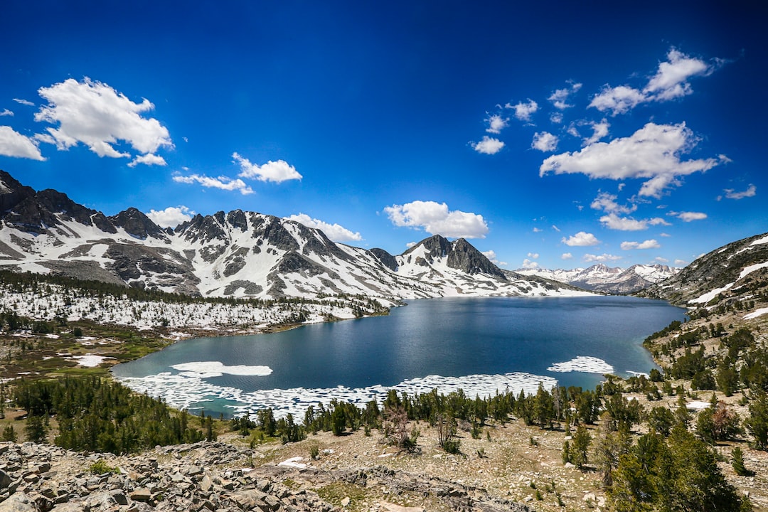 a lake surrounded by snow covered mountains under a blue sky