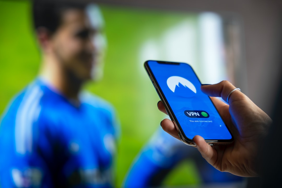 man in blue and white crew neck shirt holding black smartphone