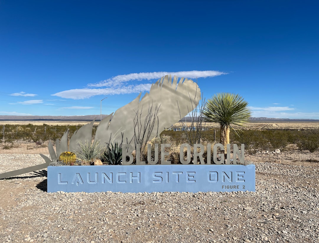 a sign in the middle of a desert with a sky background