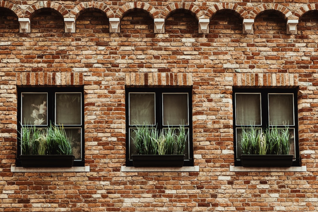 a brick building with three windows with plants in them