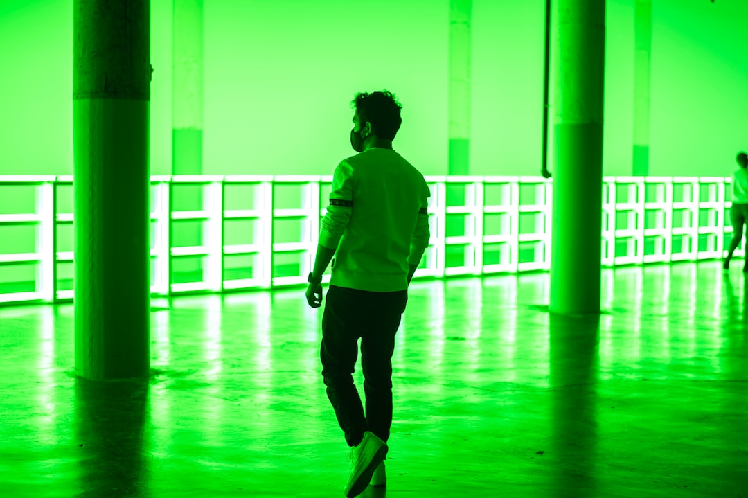 woman in green long sleeve shirt and black pants walking on hallway