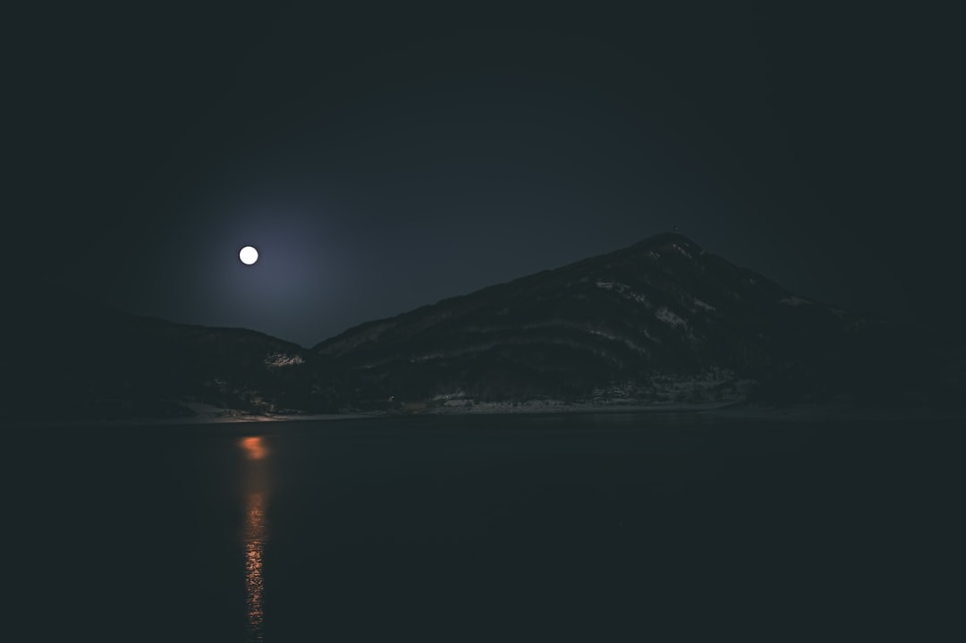 a full moon is seen over a mountain at night