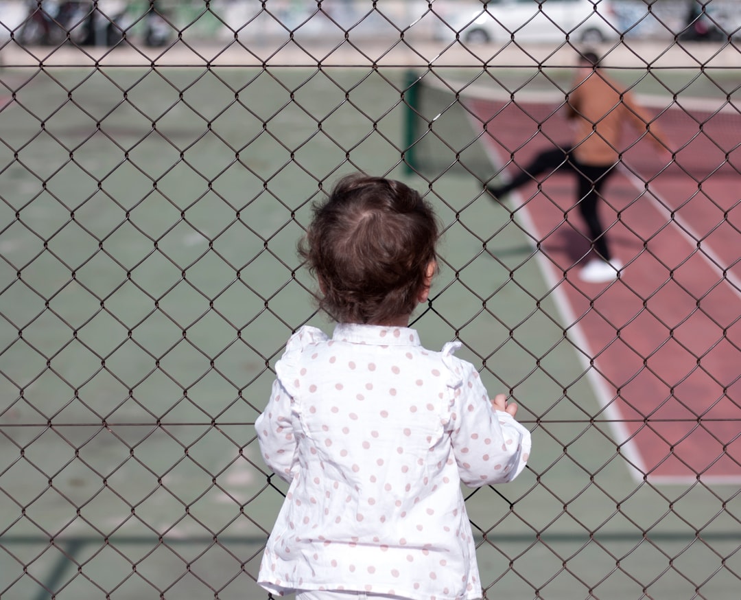 a little girl standing on a tennis court holding a racquet