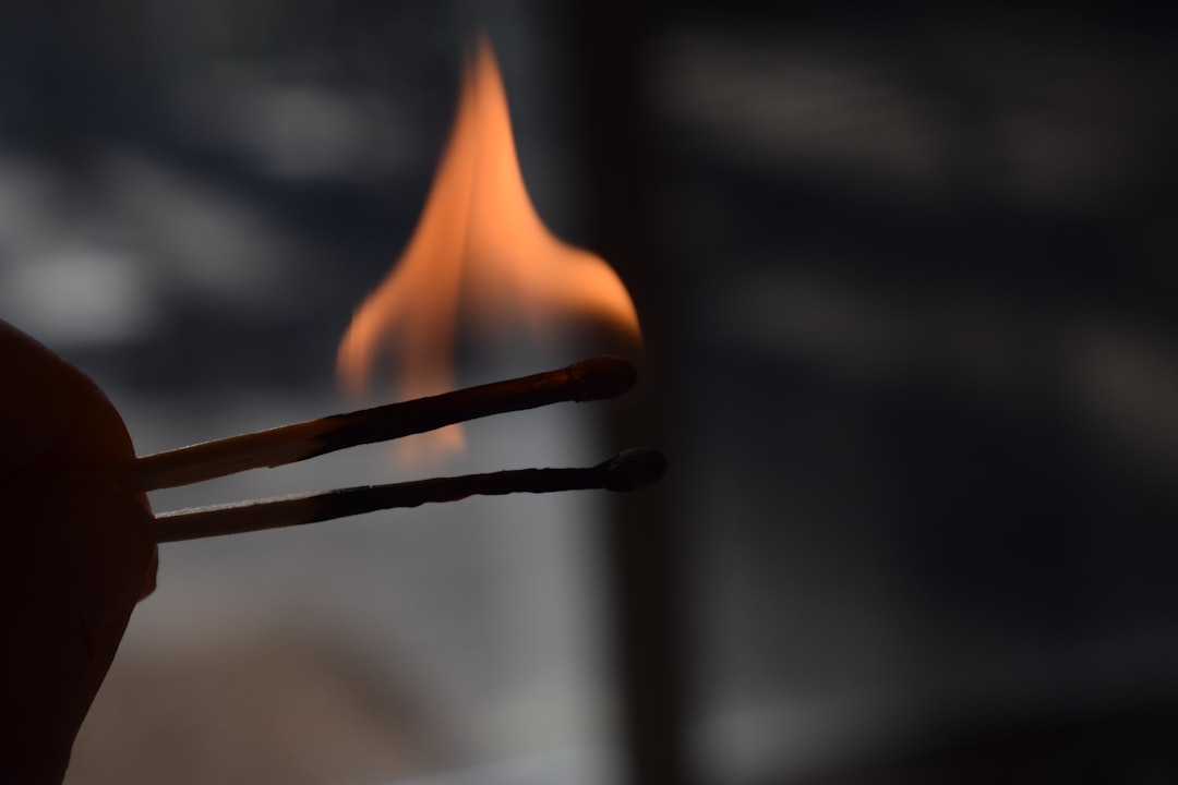 a hand holding a match with a flame in the background