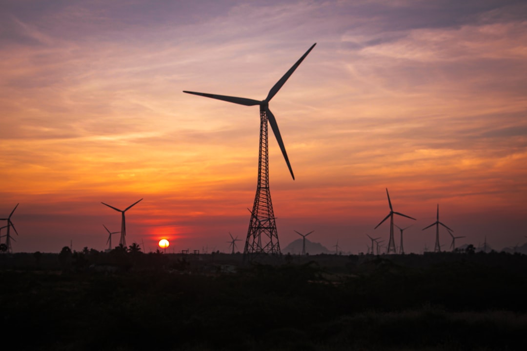 the sun is setting behind a wind farm