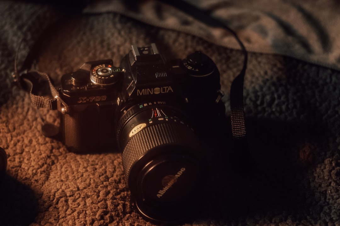 A camera sitting on a bed next to a pillow