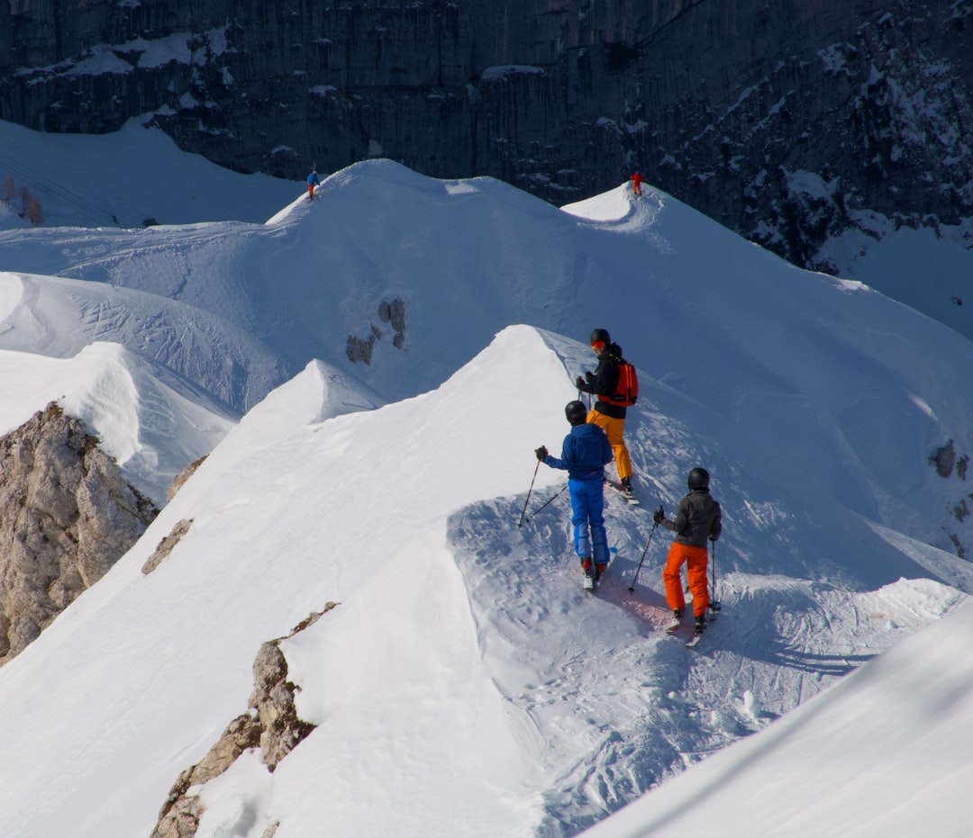 man in orange jacket and black pants on snow covered mountain during daytime