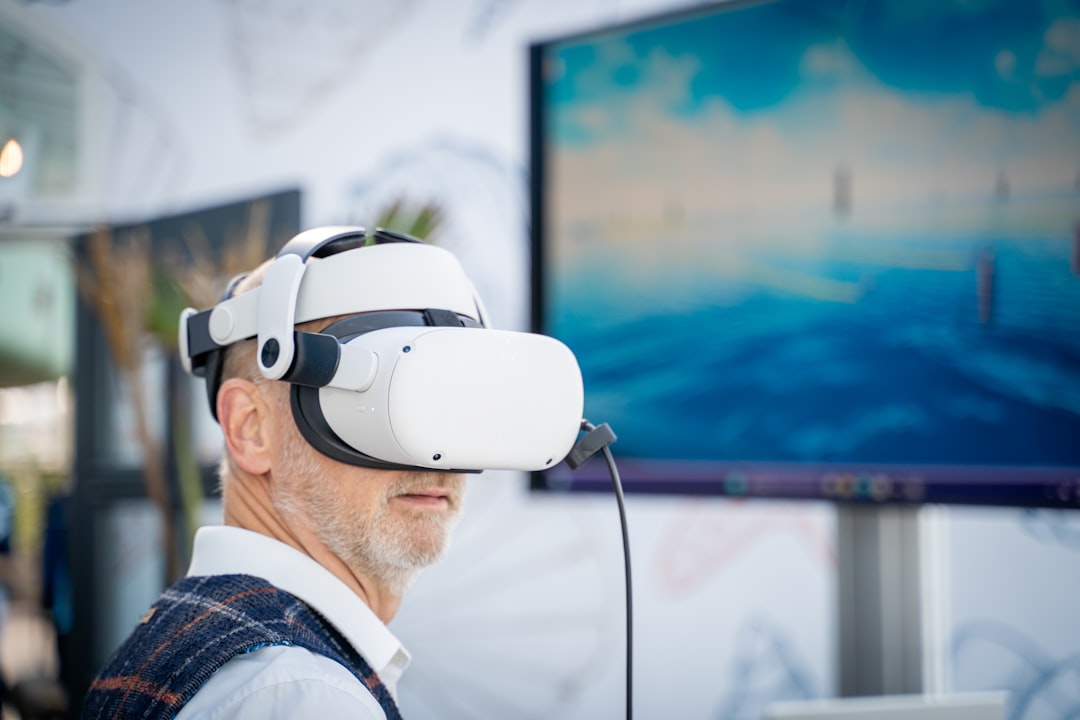 A man wearing a virtual reality headset in front of a laptop