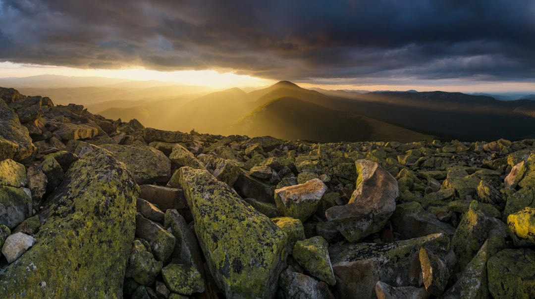 the sun shines through the clouds over a rocky terrain