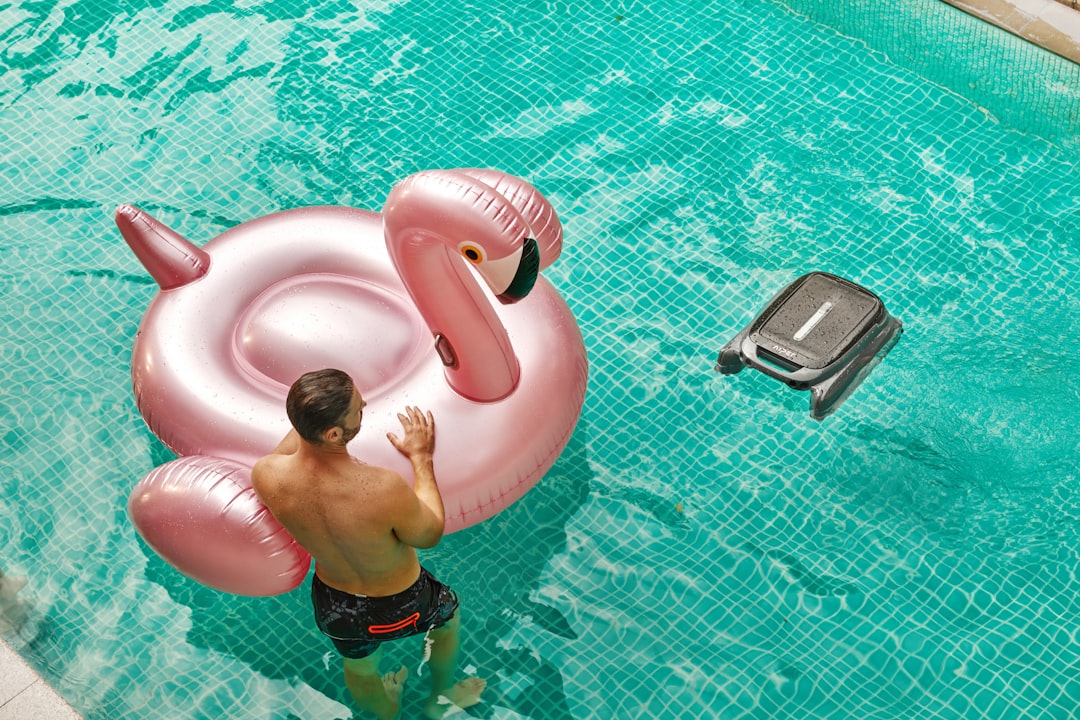 A man standing in a pool with an inflatable flamingo