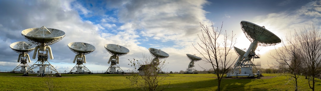 white satellite dish on green grass field under blue sky and white clouds during daytime