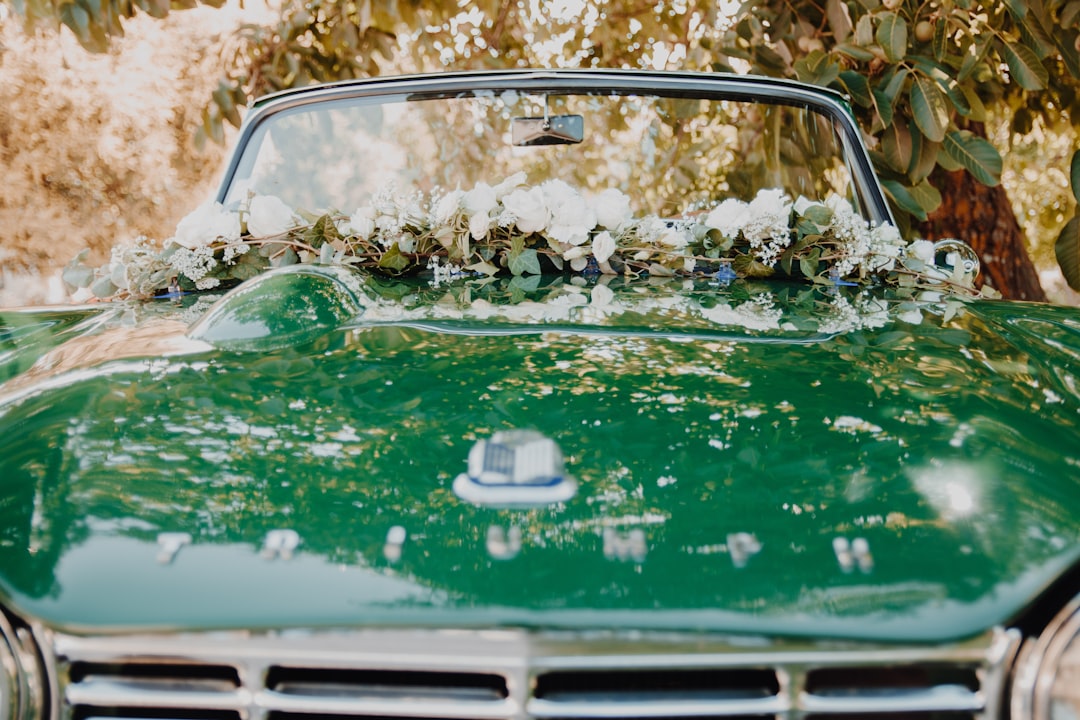 a green car with a bunch of flowers on the hood