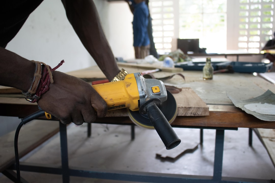 A man is using a drill to drill a piece of wood