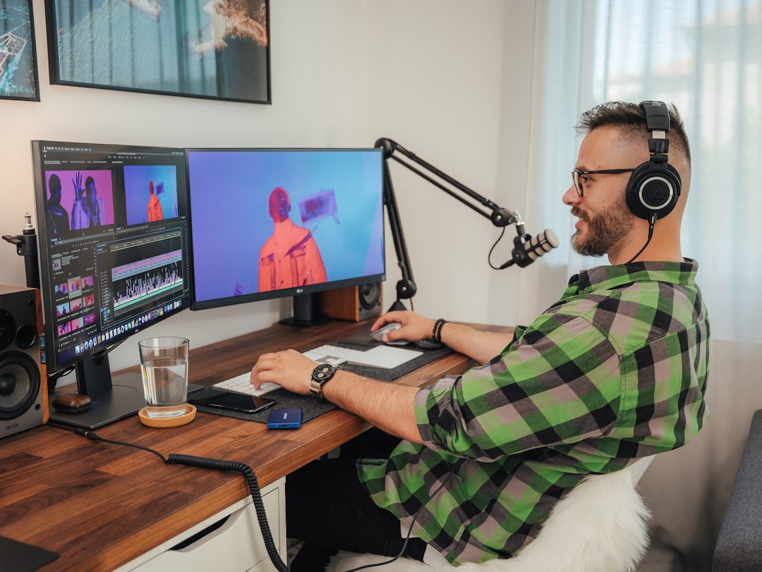 a man wearing headphones and sitting at a desk with a computer